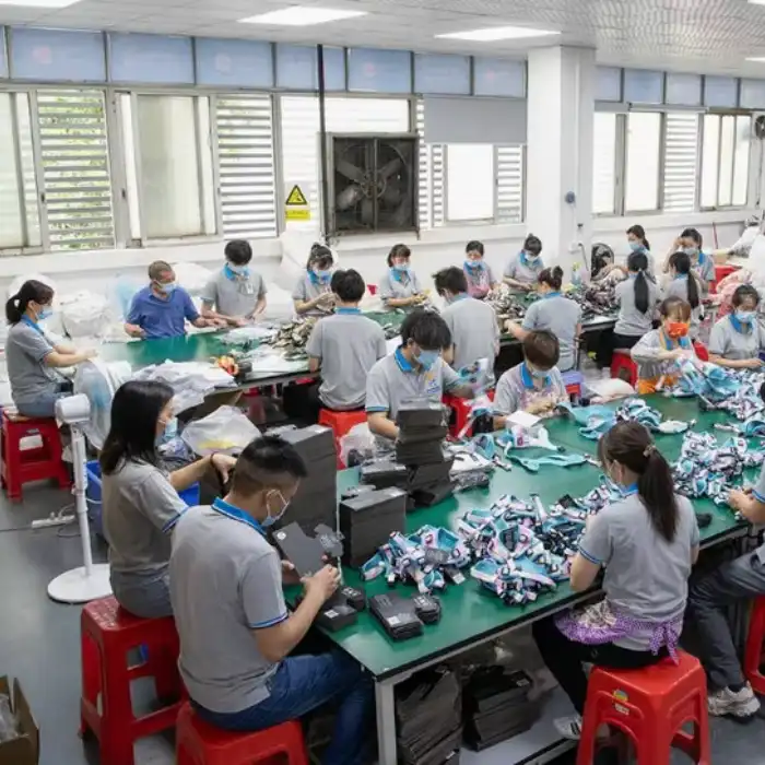 Factory workers assembling electronic products at tables.