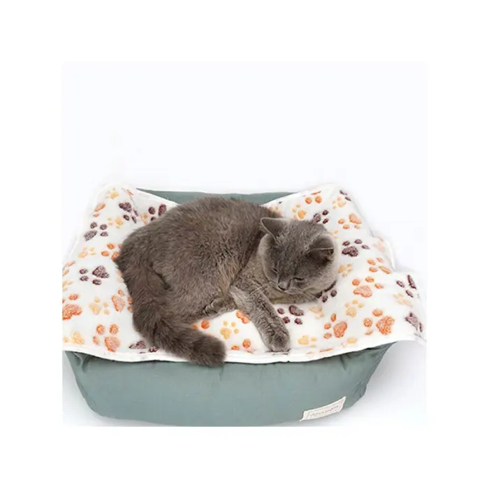 Graue Katze schläft auf gemusterter Decke.